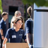 GVSU Alumnus carrying mini fridge with GVSU Alumna carrying a cardboard box labels "eggs"